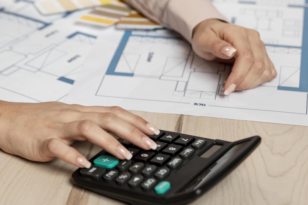 Female hand on calculator with plan on table